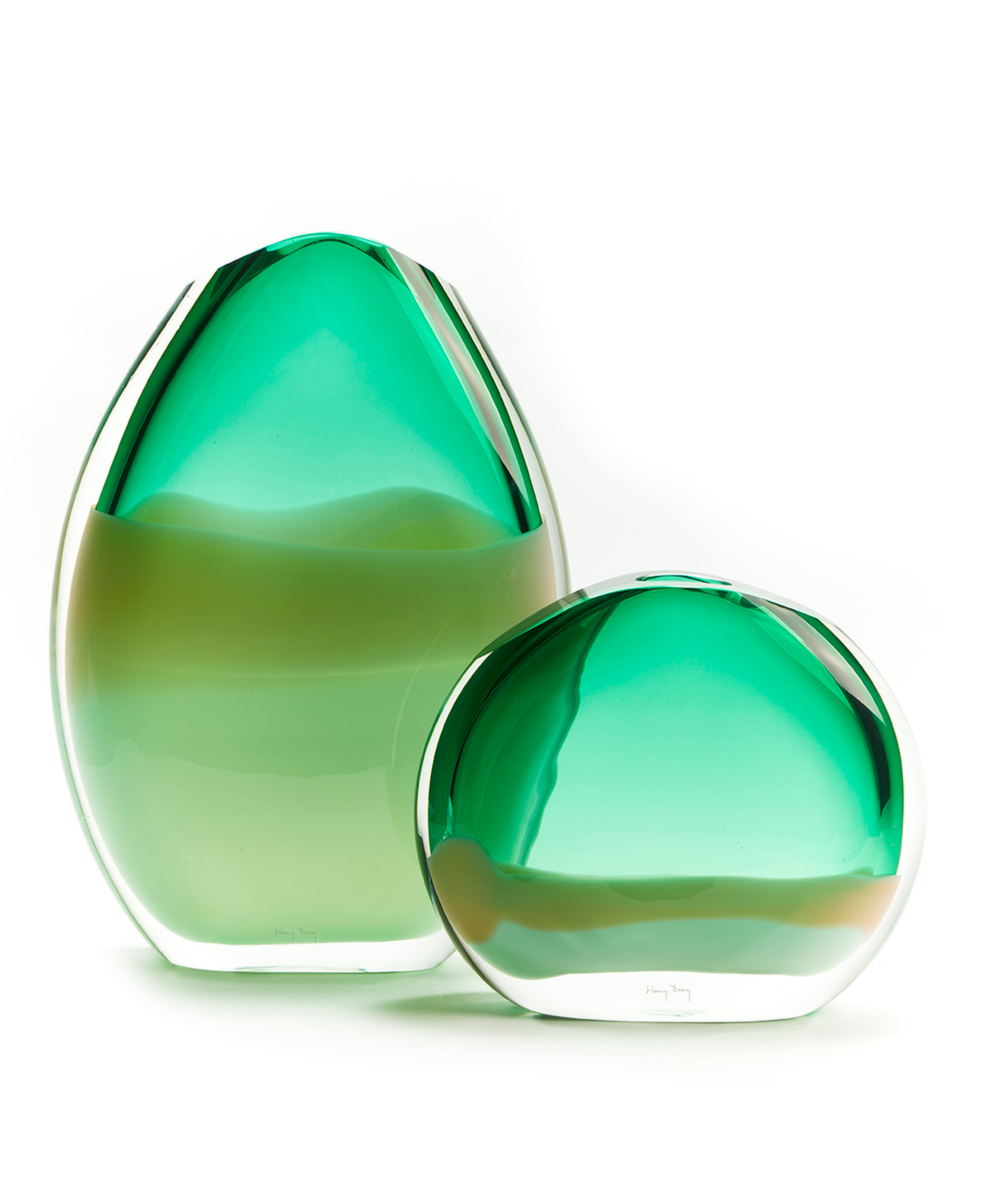 Two handmade glass objects with a oval and round shape in a green color